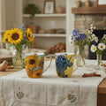Fine bone china mugs featuring Sunflowers on green and Irises Van Gogh floral designs styled on a table in a warm, cozy setting